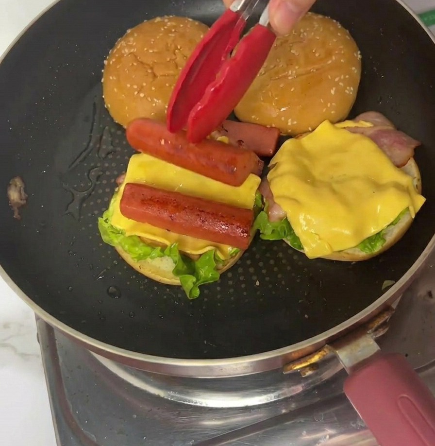 Układanie ćwiartki omletu na burgerze za pomocą czerwonych szczypiec.