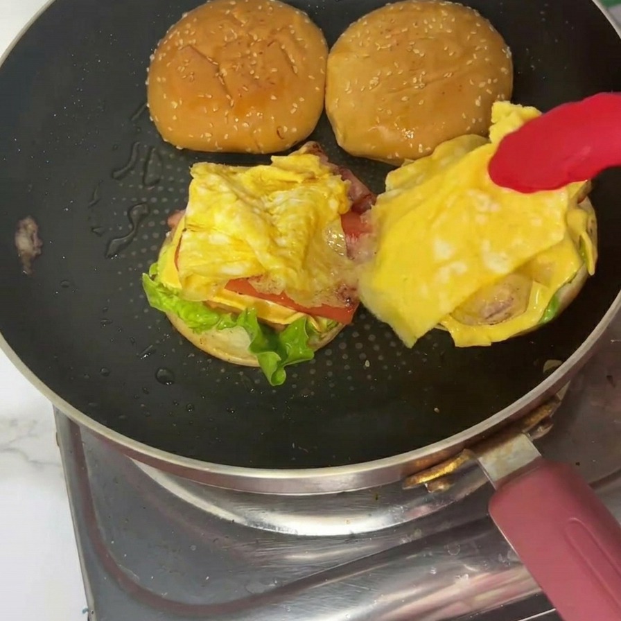Gotowy burger śniadaniowy na talerzu z nałożoną górną bułką.