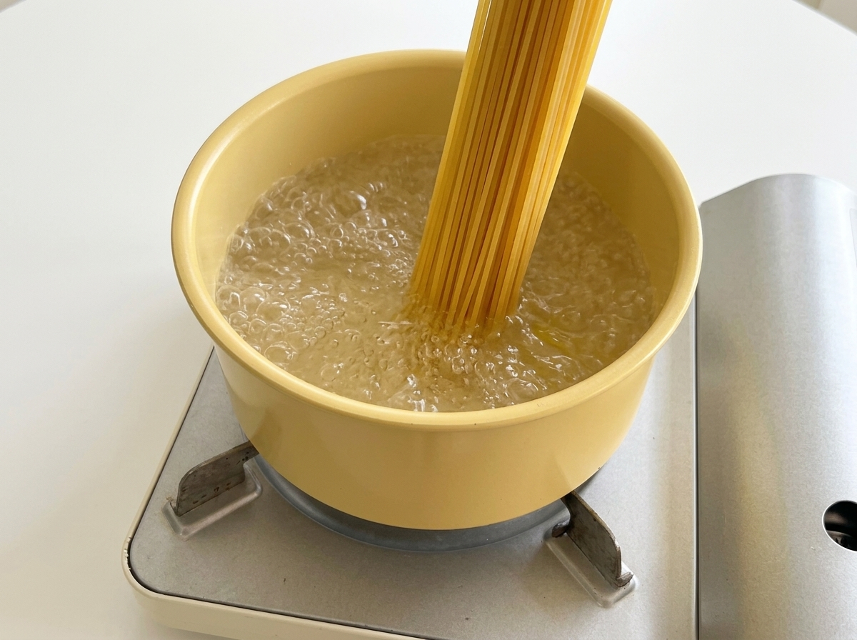 Surowy makaron spaghetti wkładany do garnka z wrzącą wodą.