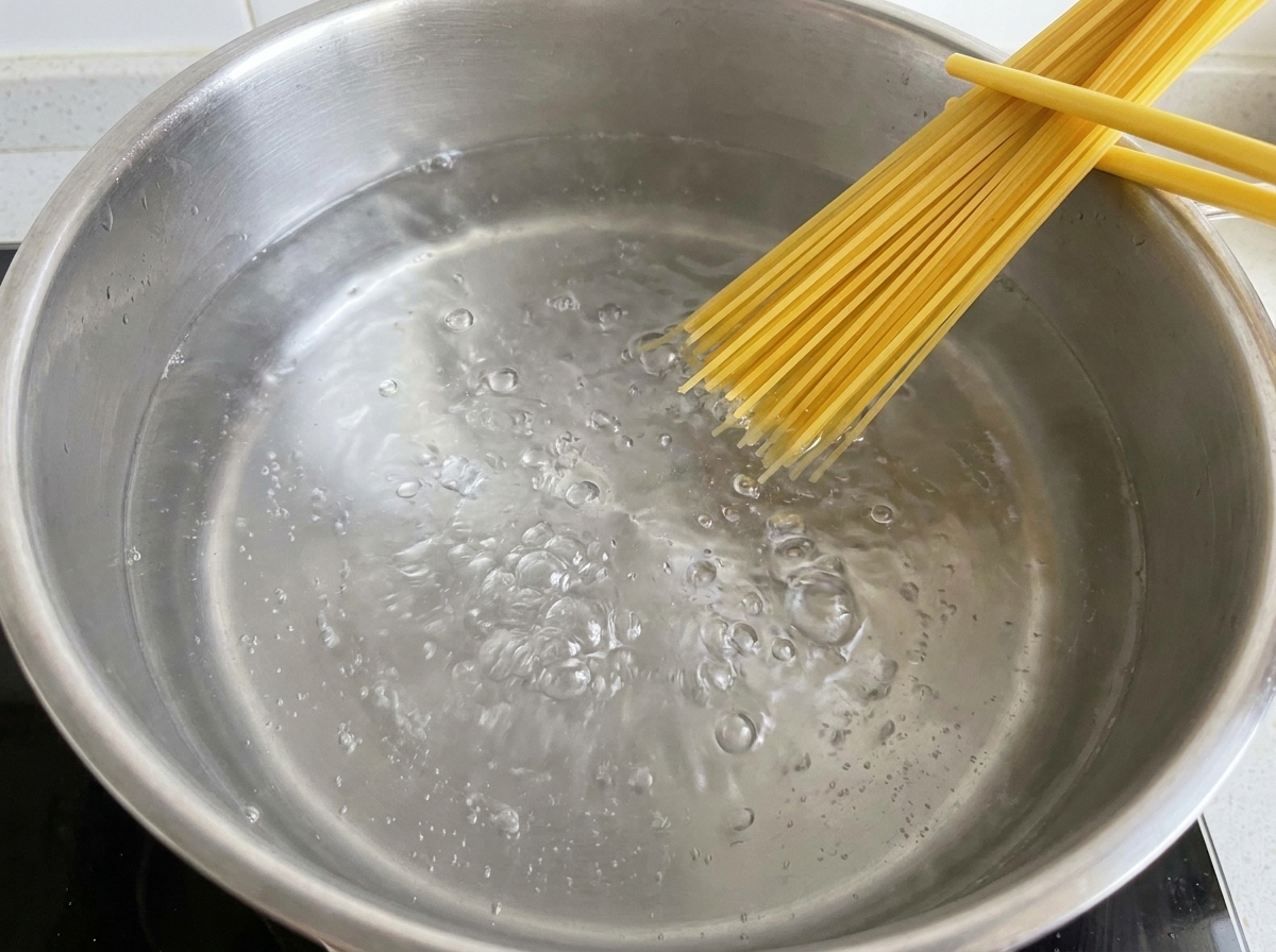 Surowy makaron spaghetti wkładany do garnka z wrzącą wodą.
