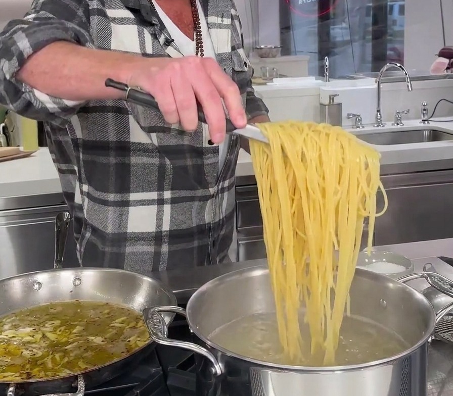 Metalowe szczypce wyciągające nitki spaghetti prosto z garnka z wrzątkiem.