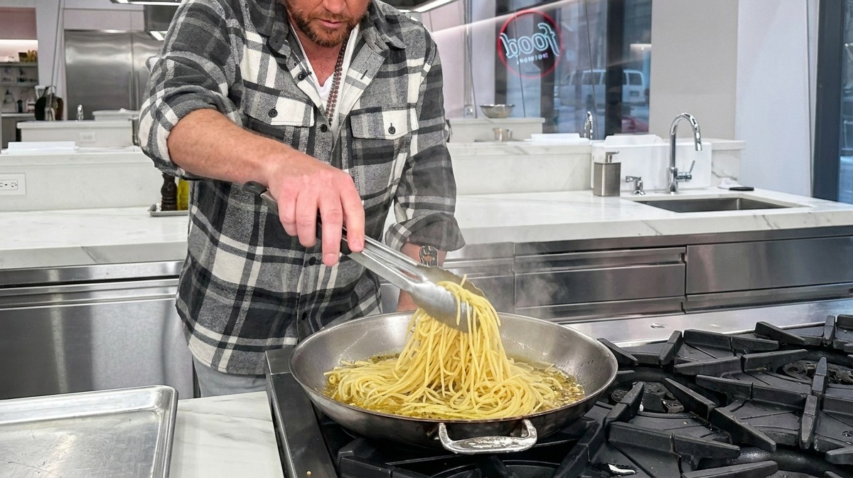 Makaron spaghetti łączący się z czosnkiem i oliwą na gorącej patelni.