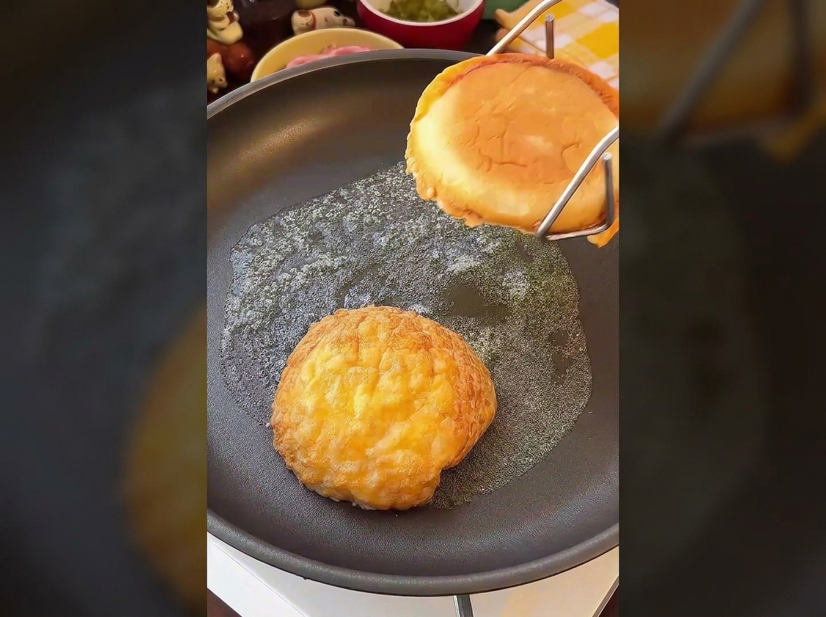 Dwie połówki bułki do burgera kładzione przekrojoną stroną do dołu na maślanej patelni.