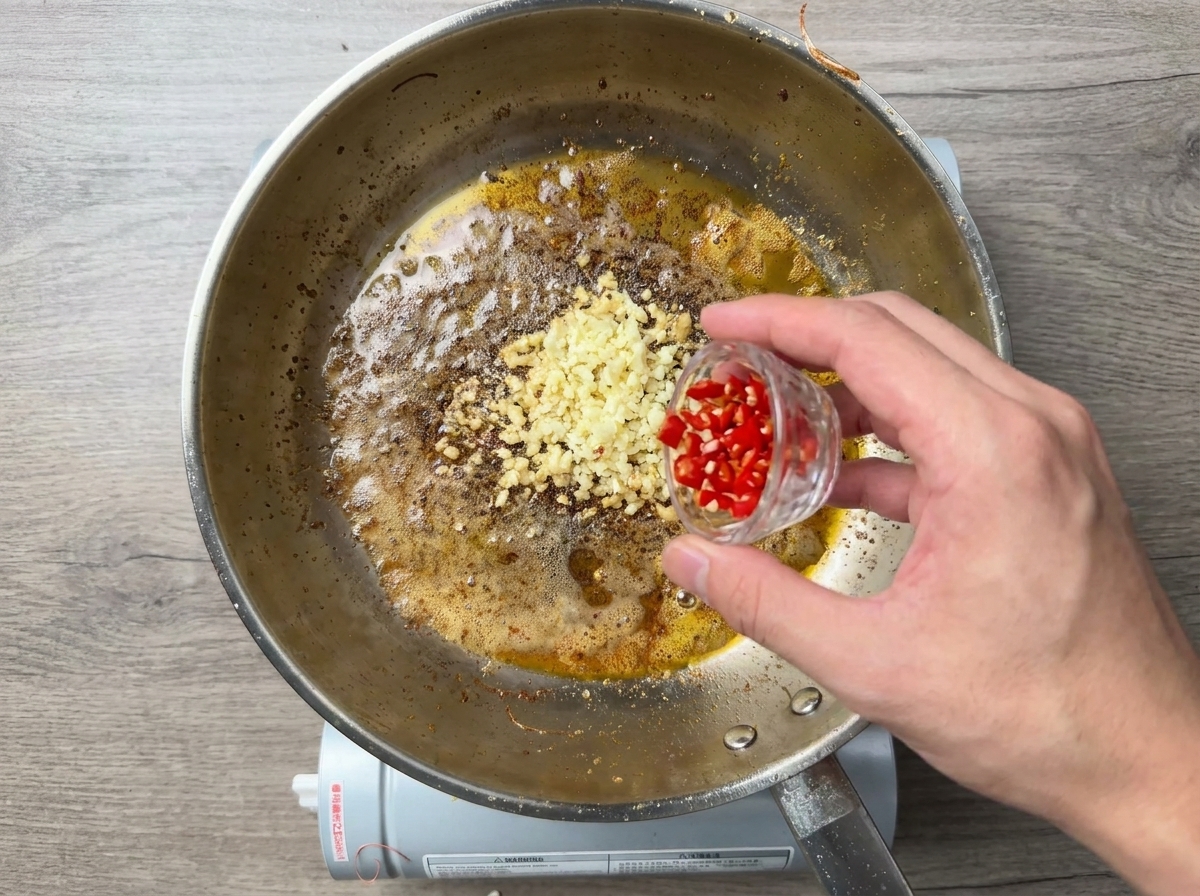 Płatki chili dodawane do czosnku na syczącej patelni.