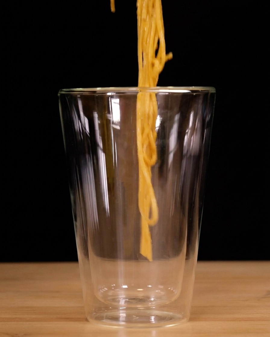 Spaghetti zwijane szczypcami i wkładane pionowo do wysokiej szklanki z podwójnymi ściankami.