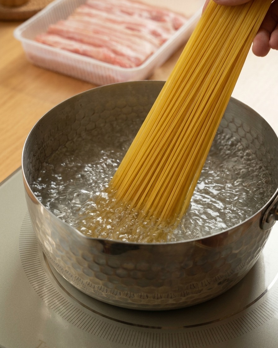 Dłoń wkładająca wiązkę suchego makaronu spaghetti do garnka z mocno wrzącą wodą.