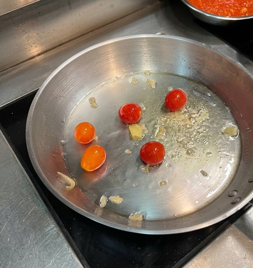 Pomidorki koktajlowe smażące się na patelni z dodatkiem płatków chili.