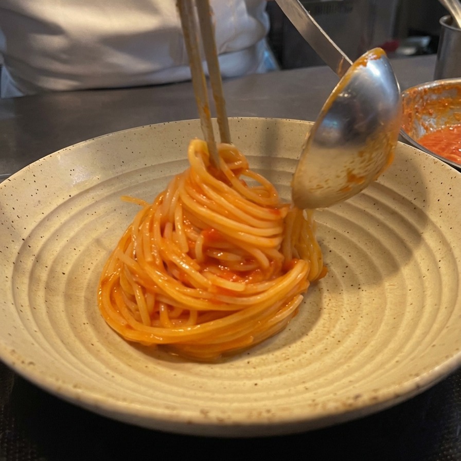 Nawijanie spaghetti na szczypce i chochlę w celu stworzenia eleganckiego kopca na talerzu.