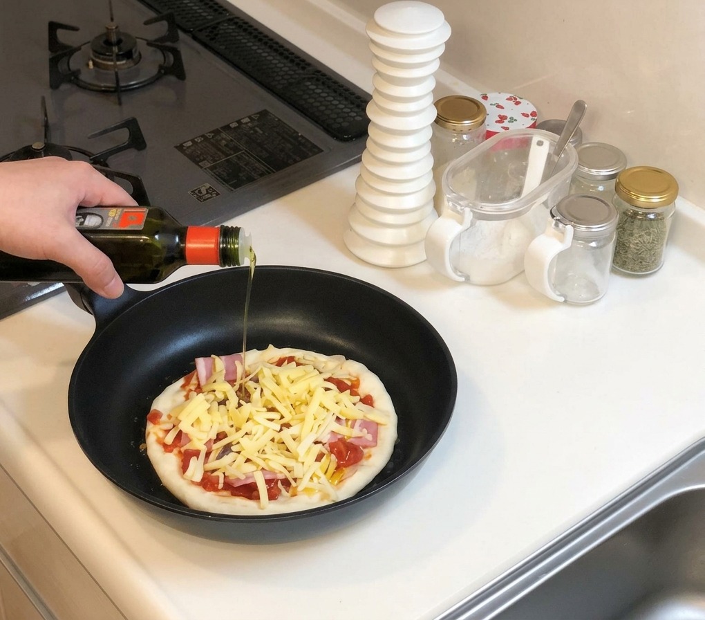 Dłoń trzymająca butelkę oliwy, skrapiająca nieupieczoną pizzę z serem na czarnej patelni.