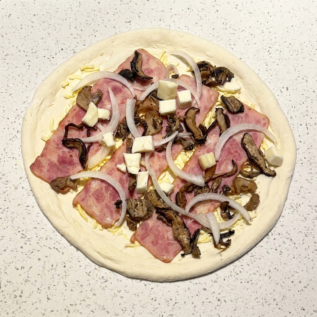 W pełni złożona surowa pizza z boczkiem, grzybami, cebulą i kostkami świeżej mozzarelli.