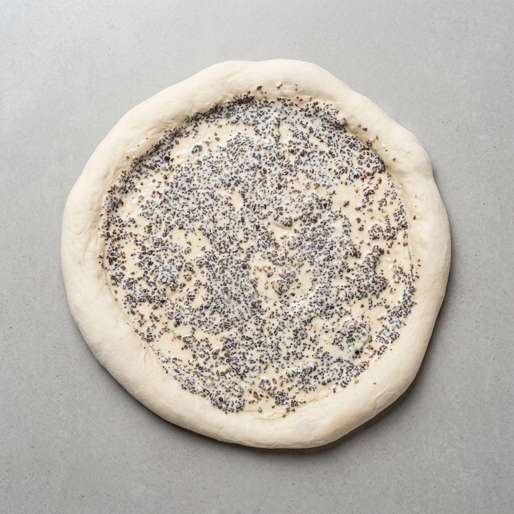 Ciasto na pizzę pokryte równomiernie sosem z czarnych trufli.