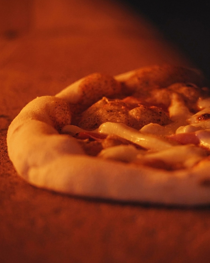 Zbliżenie na bąblującą pizzę z puszystym rantem piekącą się w gorącym piecu.