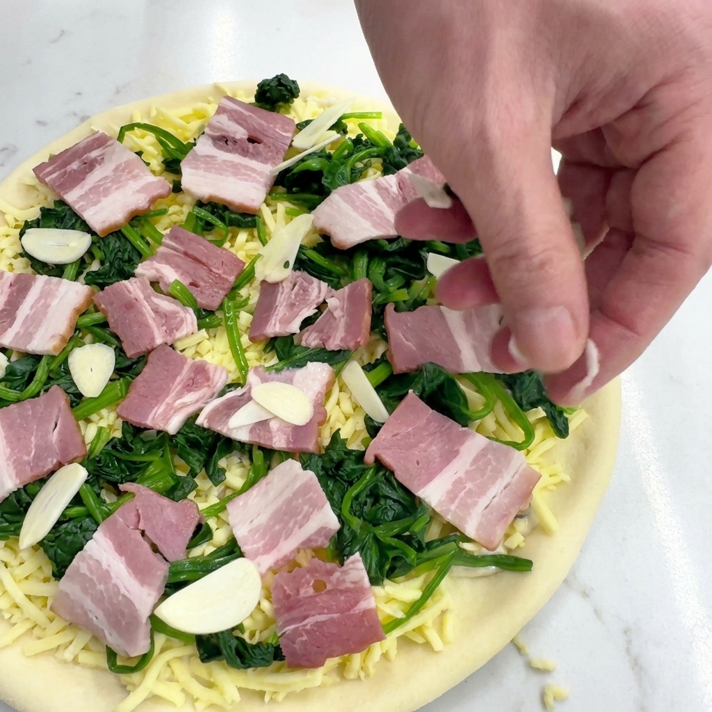 Ręka posypująca pizzę cienkimi plasterkami surowego czosnku.