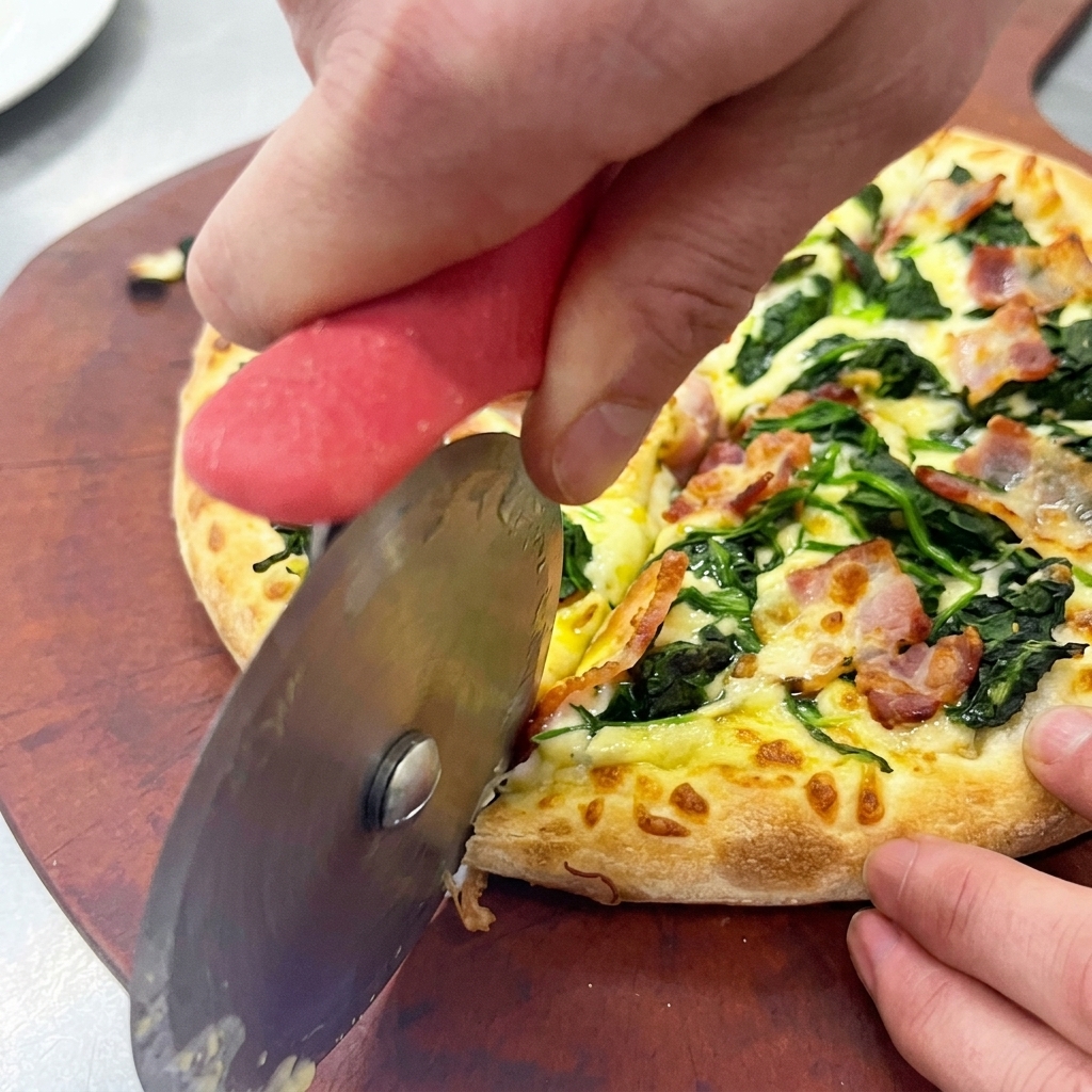 Krojenie świeżej pizzy na drewnianej desce za pomocą okrągłego noża do pizzy.