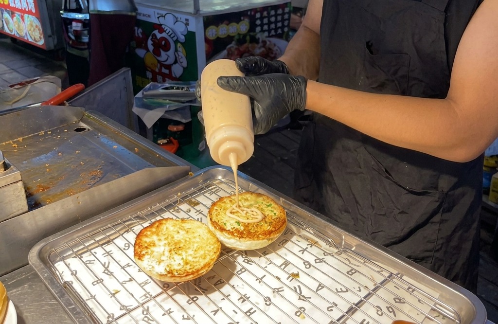 Wyciskanie charakterystycznego sosu burgerowego na opieczone połówki bułek.