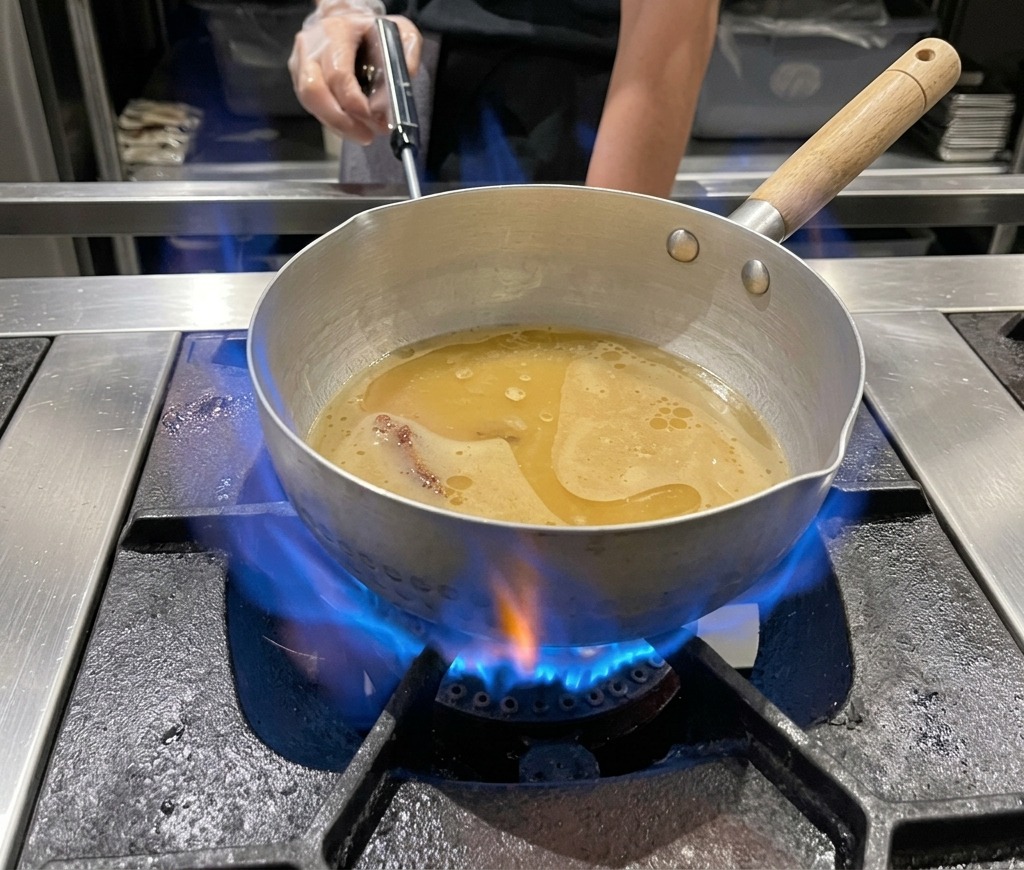 Garnek z bulionem miso gotujący się na gazowym palniku.