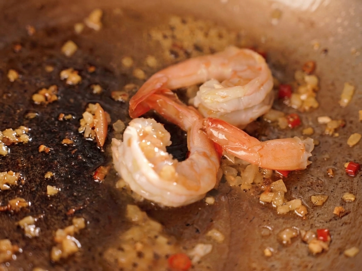 Krewetki smażone na patelni z posiekanym chili, cebulą i żółtymi kawałkami solonych żółtek.