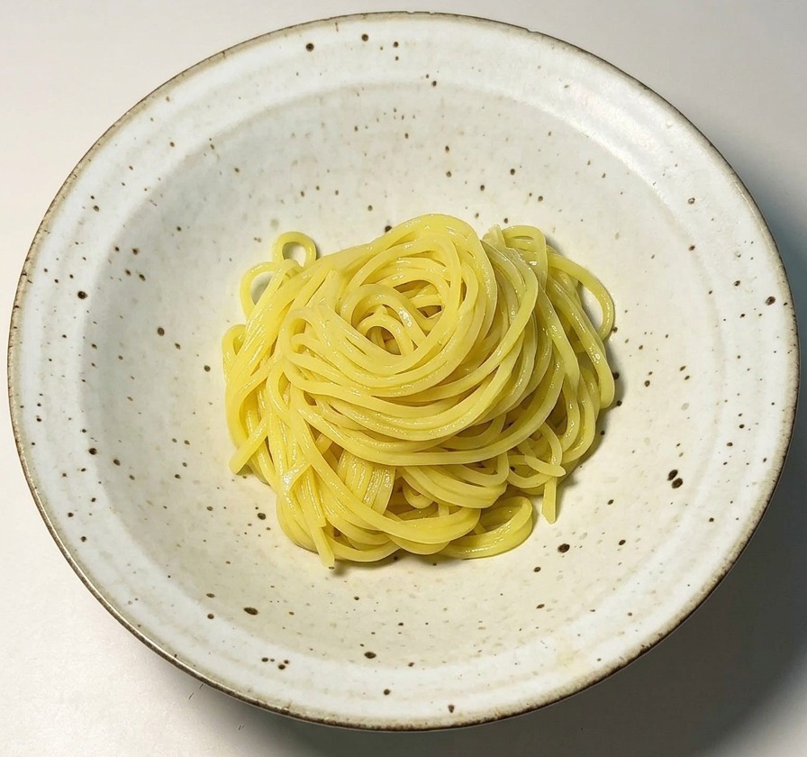 Starannie ułożony makaron ramen w nakrapianej białej ceramicznej misce.