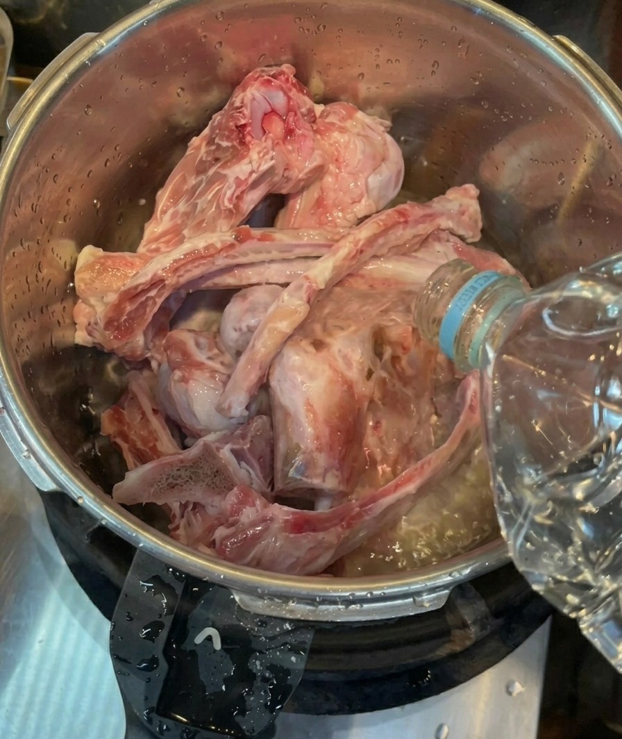 Wlewanie wody butelkowanej do szybkowaru z kośćmi wieprzowymi.