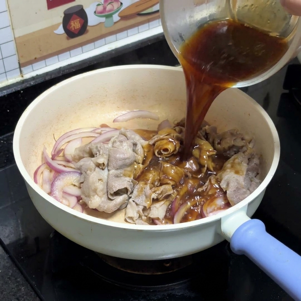 Ciemny sos teriyaki wlewany z przezroczystej szklanej miski na podsmażoną czerwoną cebulę i plastry wołowiny na białej patelni.