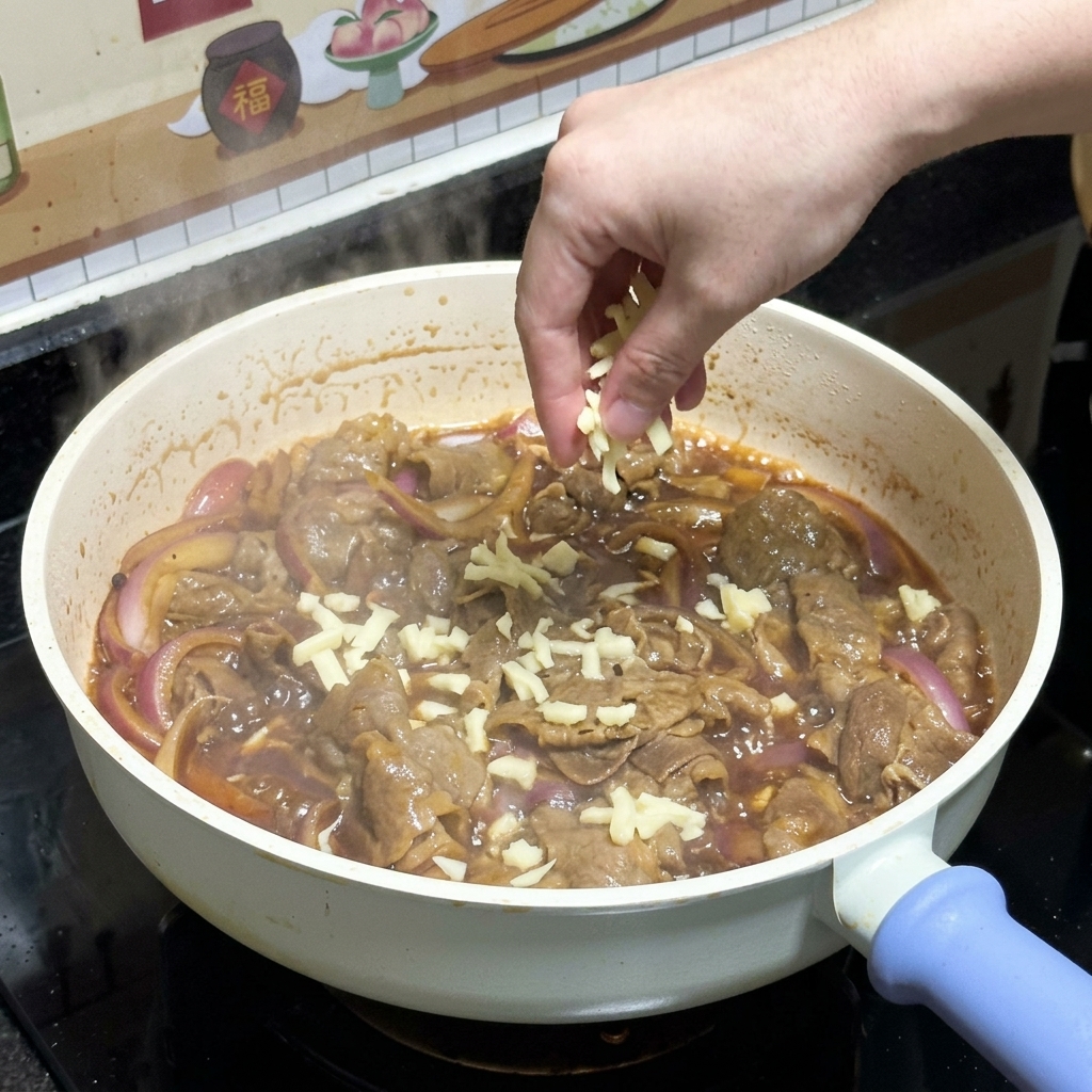 Dłoń posypująca tartą białą mozzarellą usmażoną wołowinę teriyaki z czerwoną cebulą na patelni.