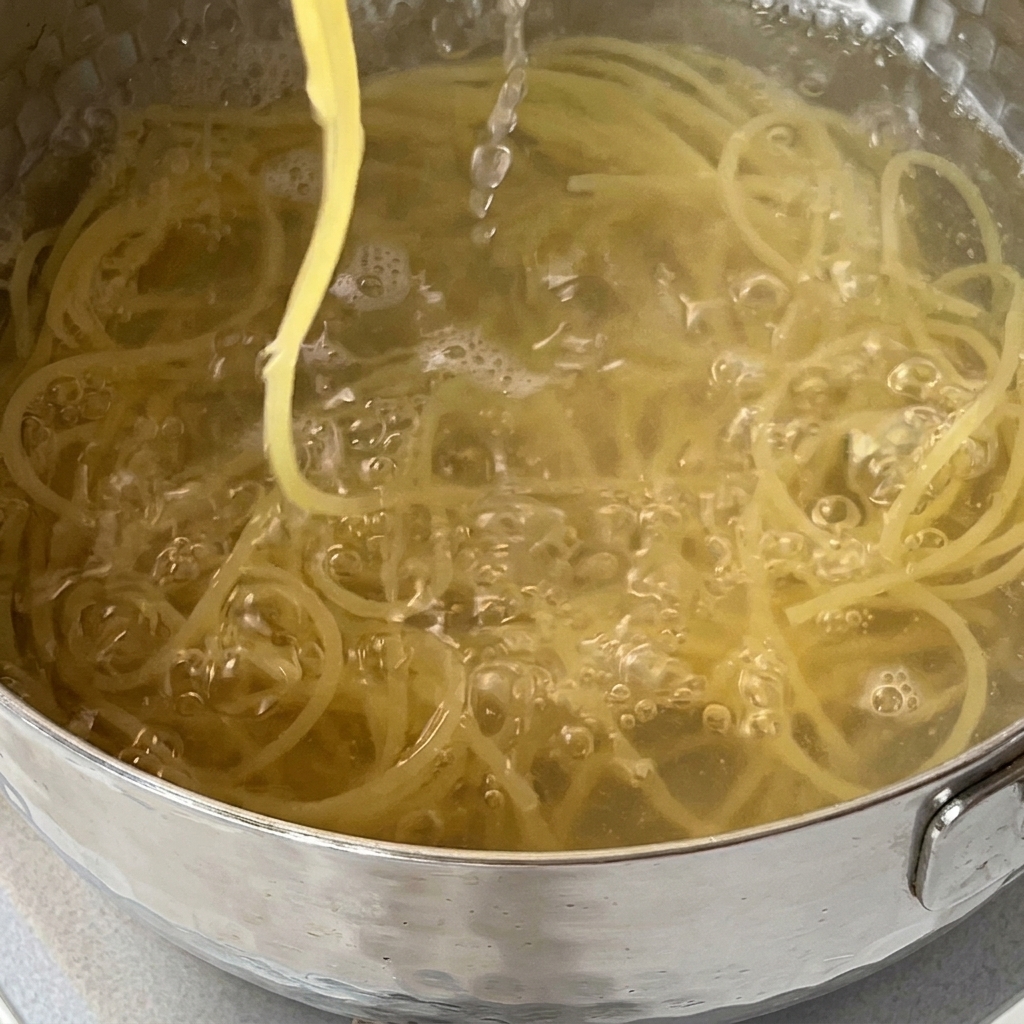 Odcedzanie makaronu spaghetti na durszlaku w zlewie kuchennym.