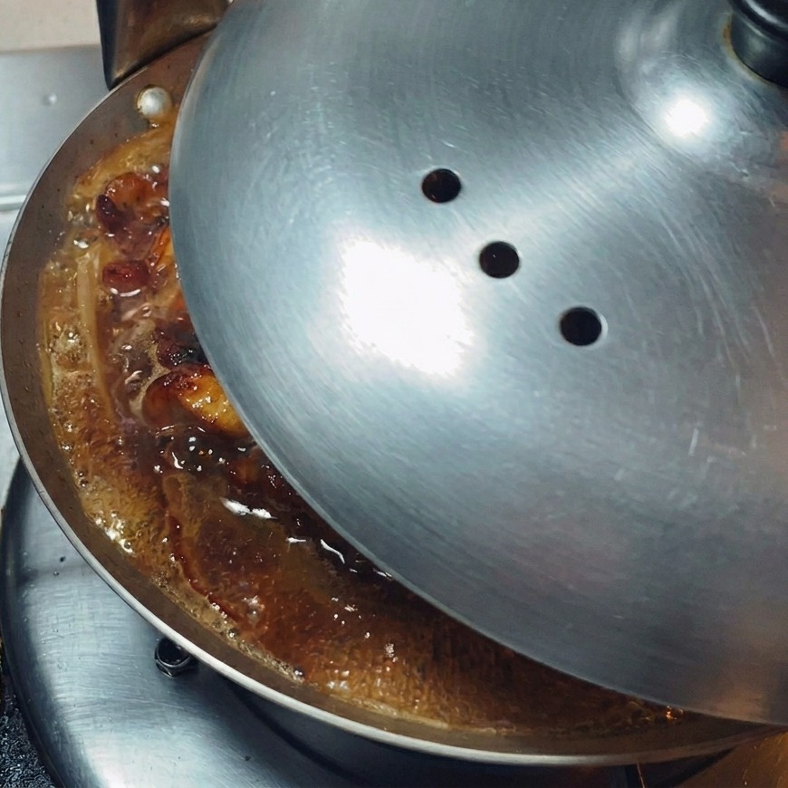 Dopasowana metalowa pokrywka nakładana na płytką patelnię, aby zatrzymać parę i poddusić zawartość.