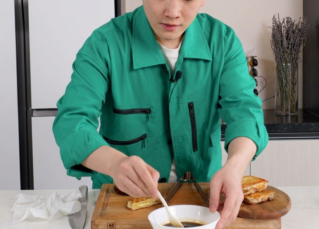 Osoba mieszająca ciemnobrązowy sos na bazie soi w białej ceramicznej miseczce za pomocą małej białej łyżeczki.