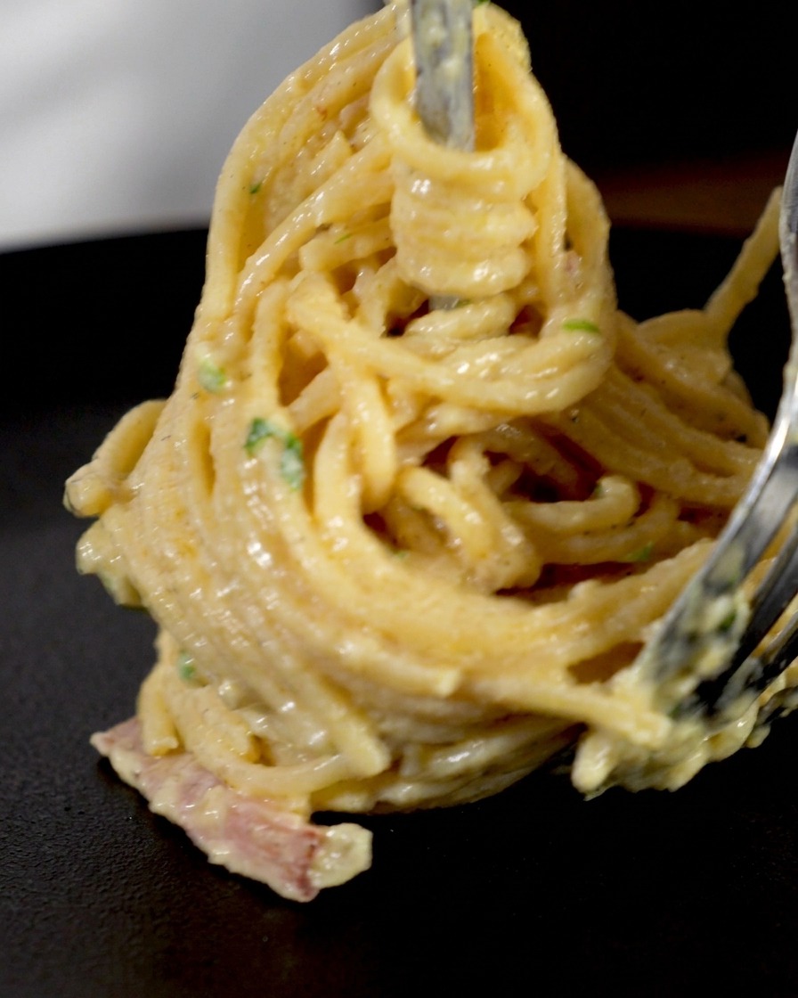 Nawijanie kremowego spaghetti na długi widelec, aby stworzyć eleganckie gniazdko.