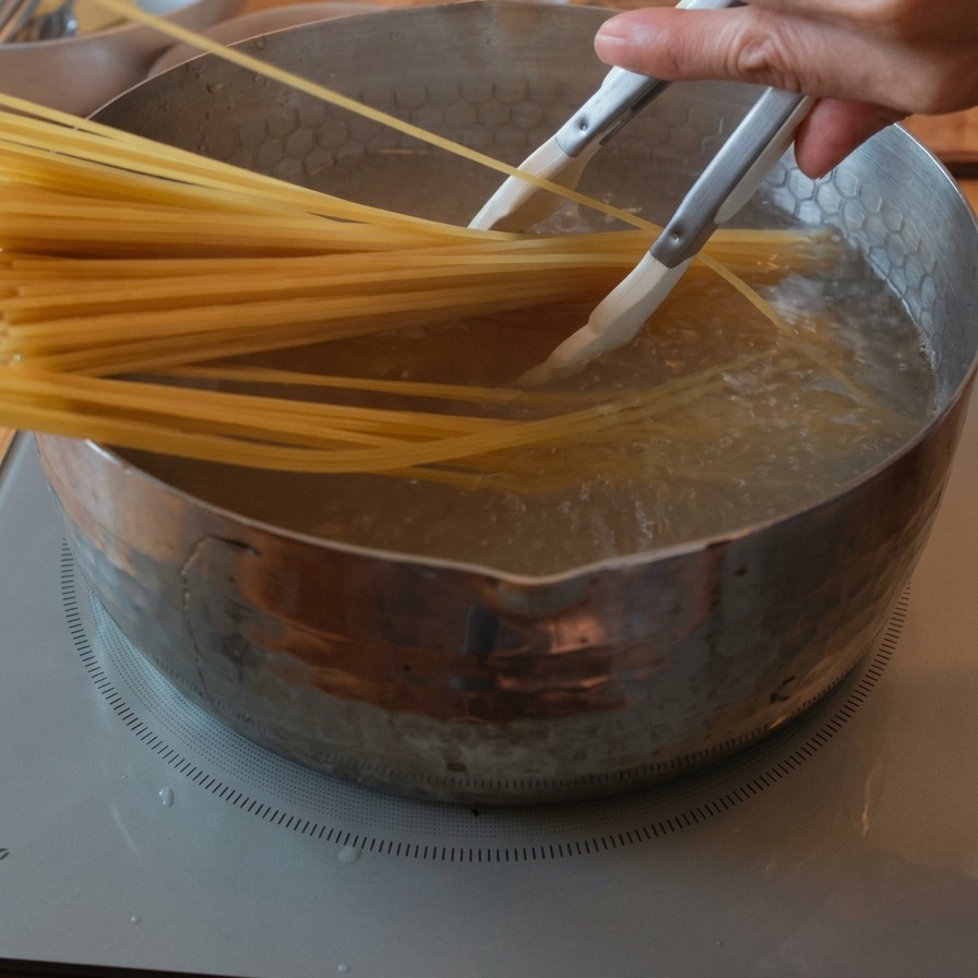 Wiązka suchego spaghetti zanurzana w garnku z wrzącą wodą za pomocą szczypiec.