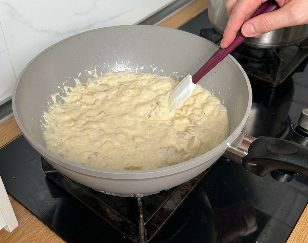 Łopatka mieszająca gęstniejący, bulgoczący sos śmietanowy z boczkiem i pieczarkami.