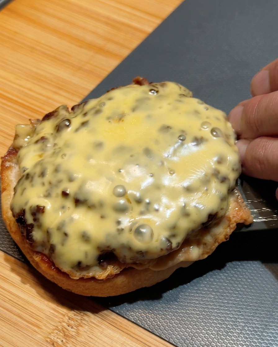Szpatułka przenosząca dwa piętrowe kotlety z serem na dolną bułkę burgera.