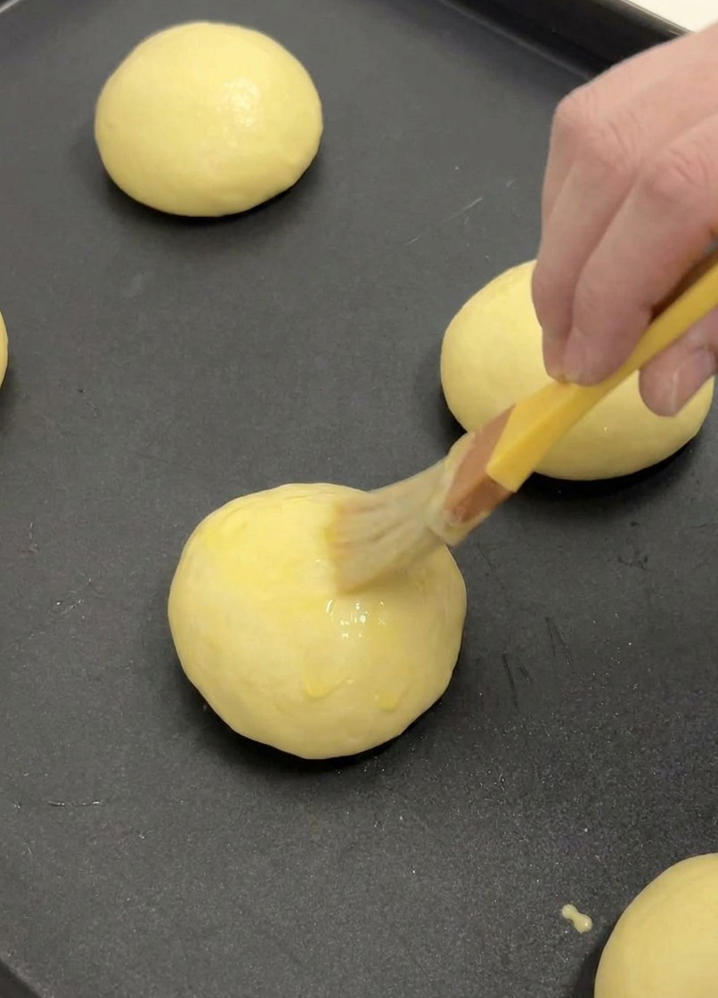 Pędzel cukierniczy nakładający cienką warstwę roztrzepanego jajka na wyrośniętą bułkę brioche.