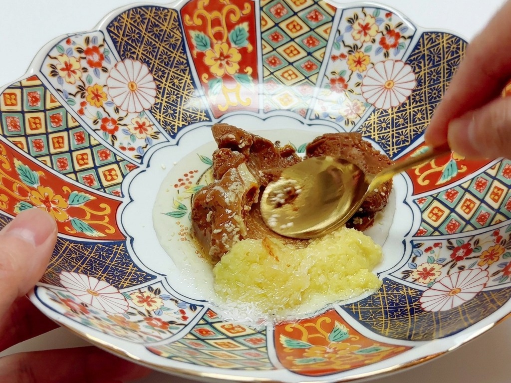 Łyżka mieszająca różne pasty i przyprawy w kolorowej, zdobionej porcelanowej misce.