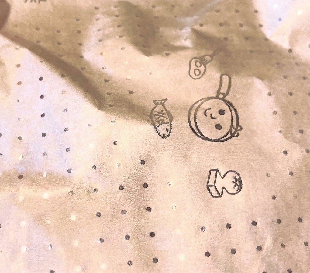 Zbliżenie na okrągłą pokrywkę z papieru do pieczenia z kuchennymi motywami, przykrywającą patelnię podczas gotowania.
