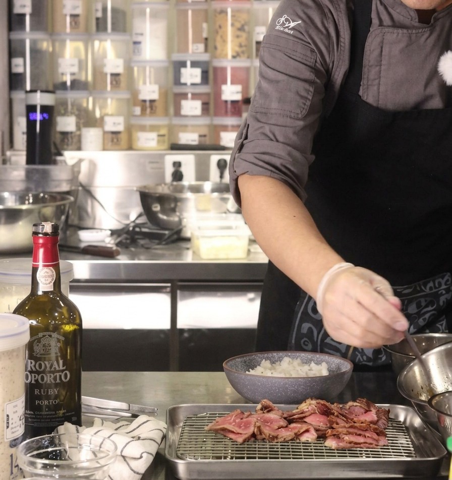Dłoń w rękawiczce skrapiająca łyżką ciemnym sosem yakiniku miskę gorącego białego ryżu.