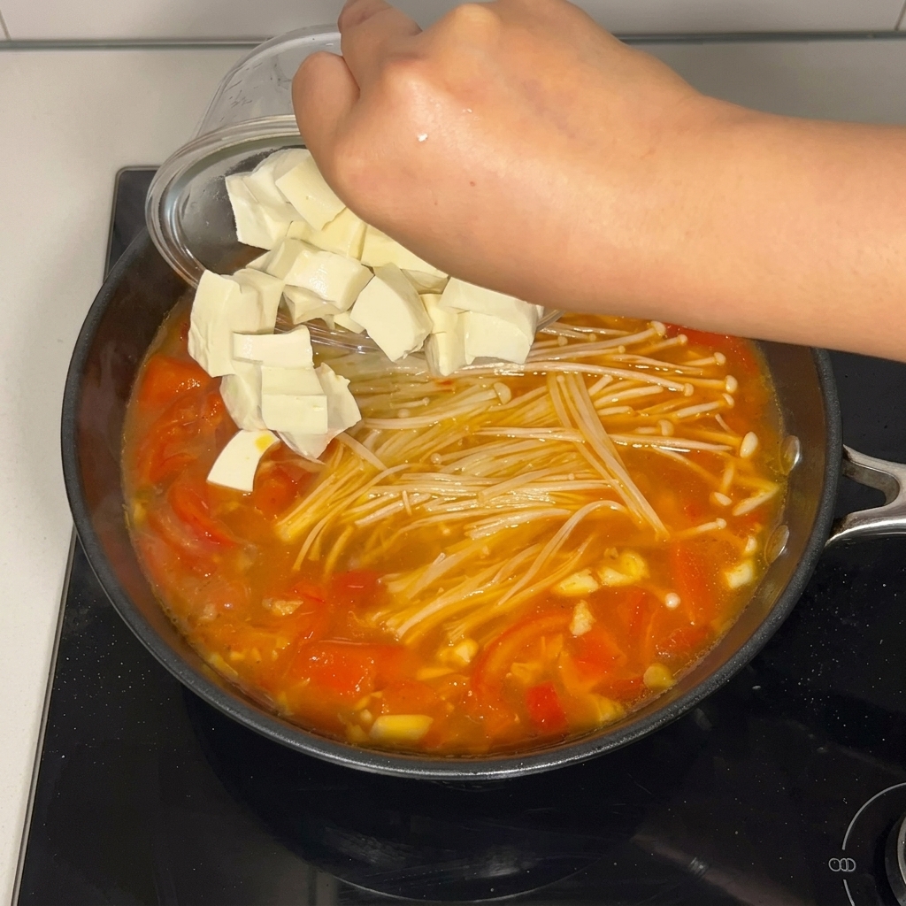 Kostki tofu wrzucane do garnka z zupą.