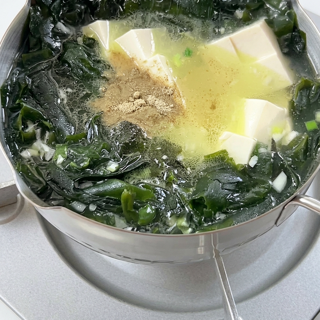 Mielony pieprz wsypywany do wrzącej zupy z glonami wakame i kostkami tofu.