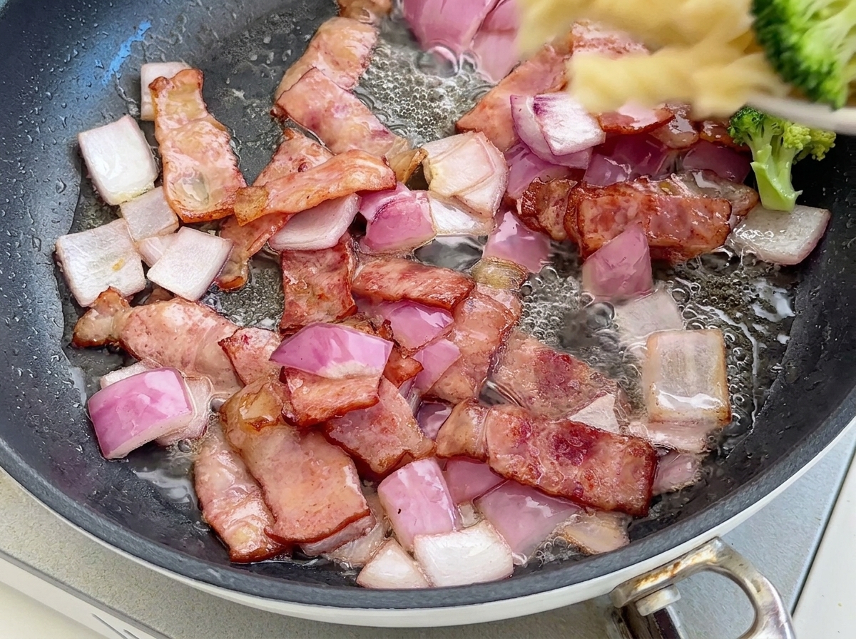 Ugotowany makaron fusilli i jaskrawozielone różyczki brokuła wrzucane na patelnię z bekonem i cebulą.