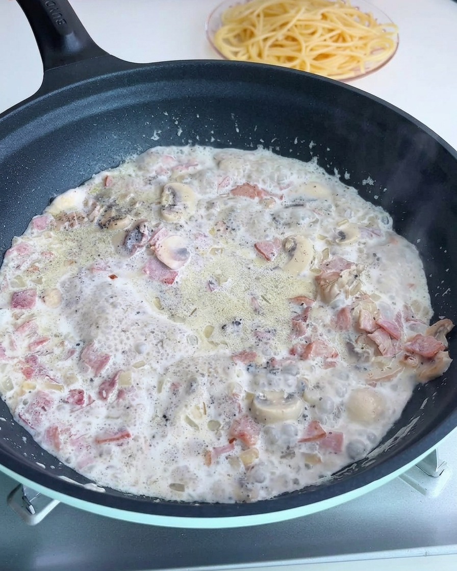 Doprawianie sosu na patelni solą i świeżo mielonym pieprzem.