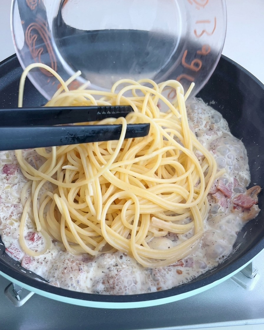 Spaghetti mieszane z kremowym sosem truflowym na patelni.