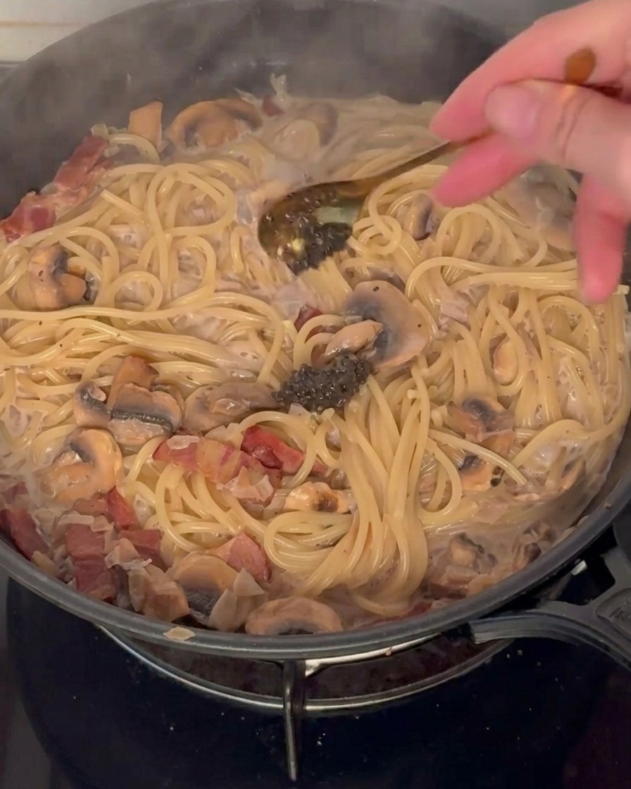 Pasta z czarnej trufli dodawana do patelni z makaronem w sosie.