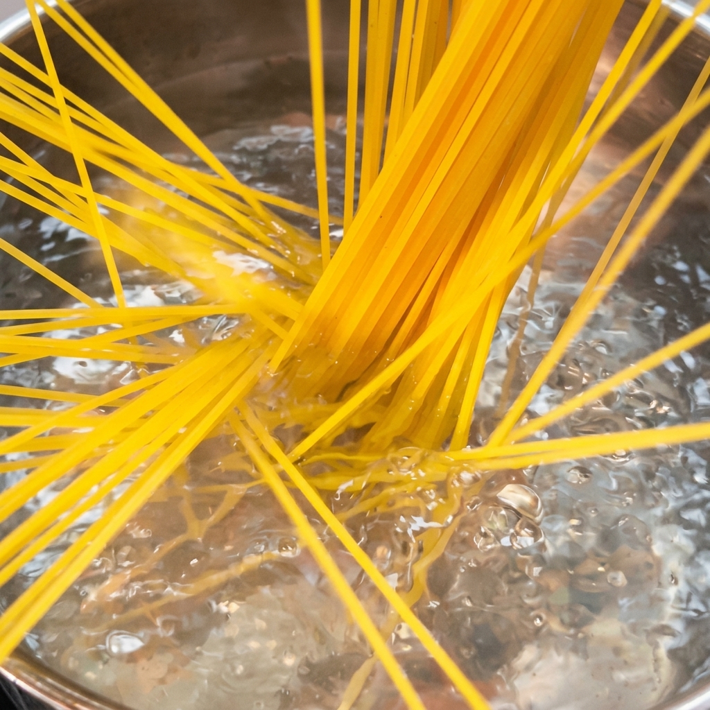 Nitki spaghetti gotujące się w dużym garnku wrzącej osolonej wody.