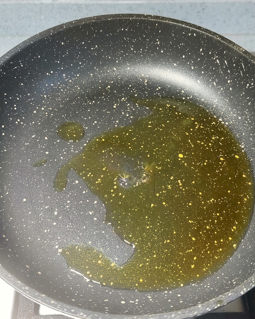 Posiekany czosnek i czerwona pasta krewetkowa skwierczące na gorącym oleju na patelni.