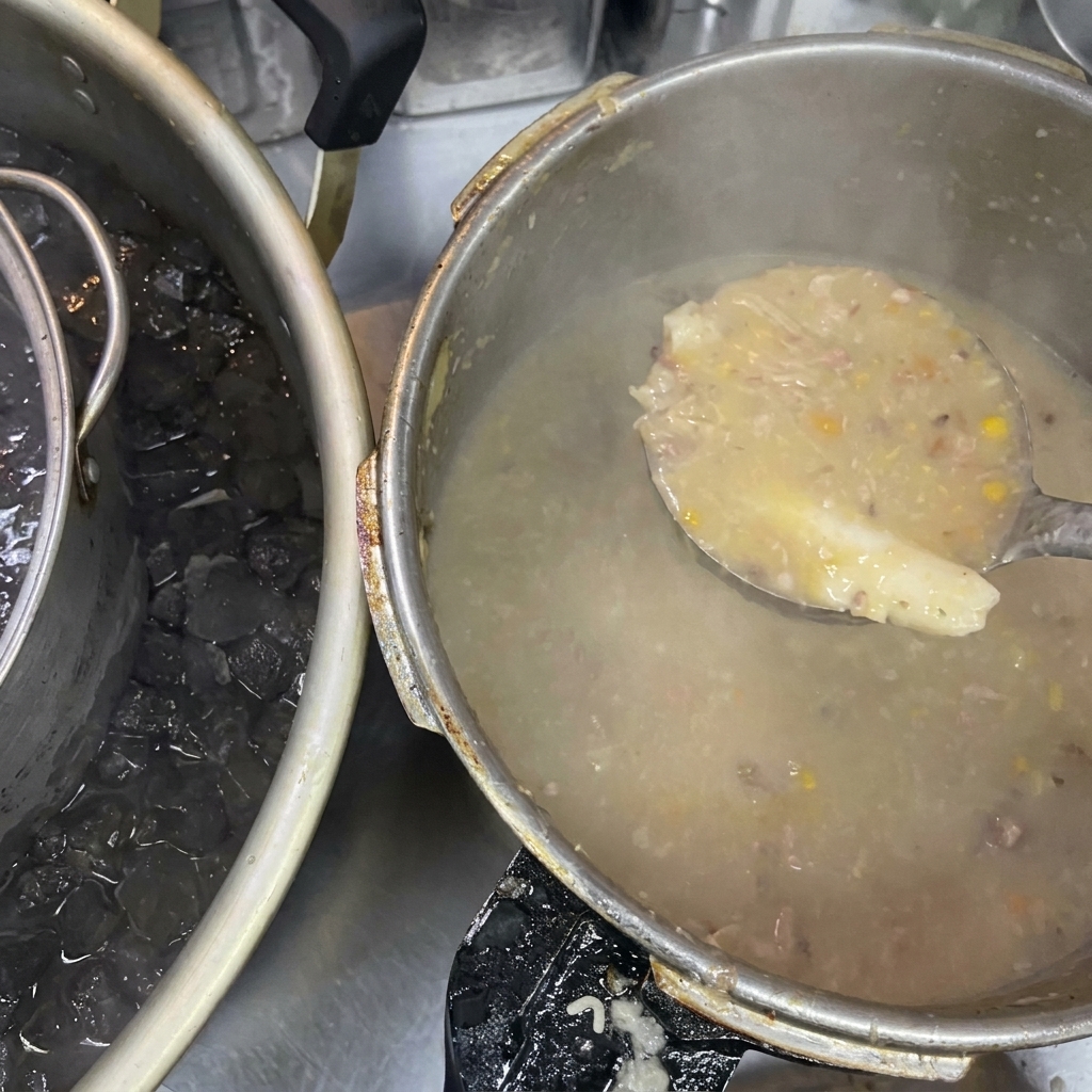 Chochla z gęstym, mętnym bulionem obok dużego garnka zanurzonego w kąpieli lodowej.