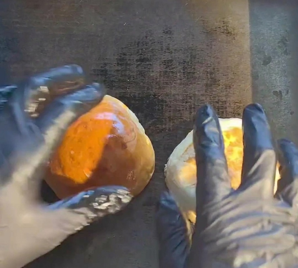 Surowy kotlet wołowy skwierczący na gorącej płaskiej patelni grillowej.