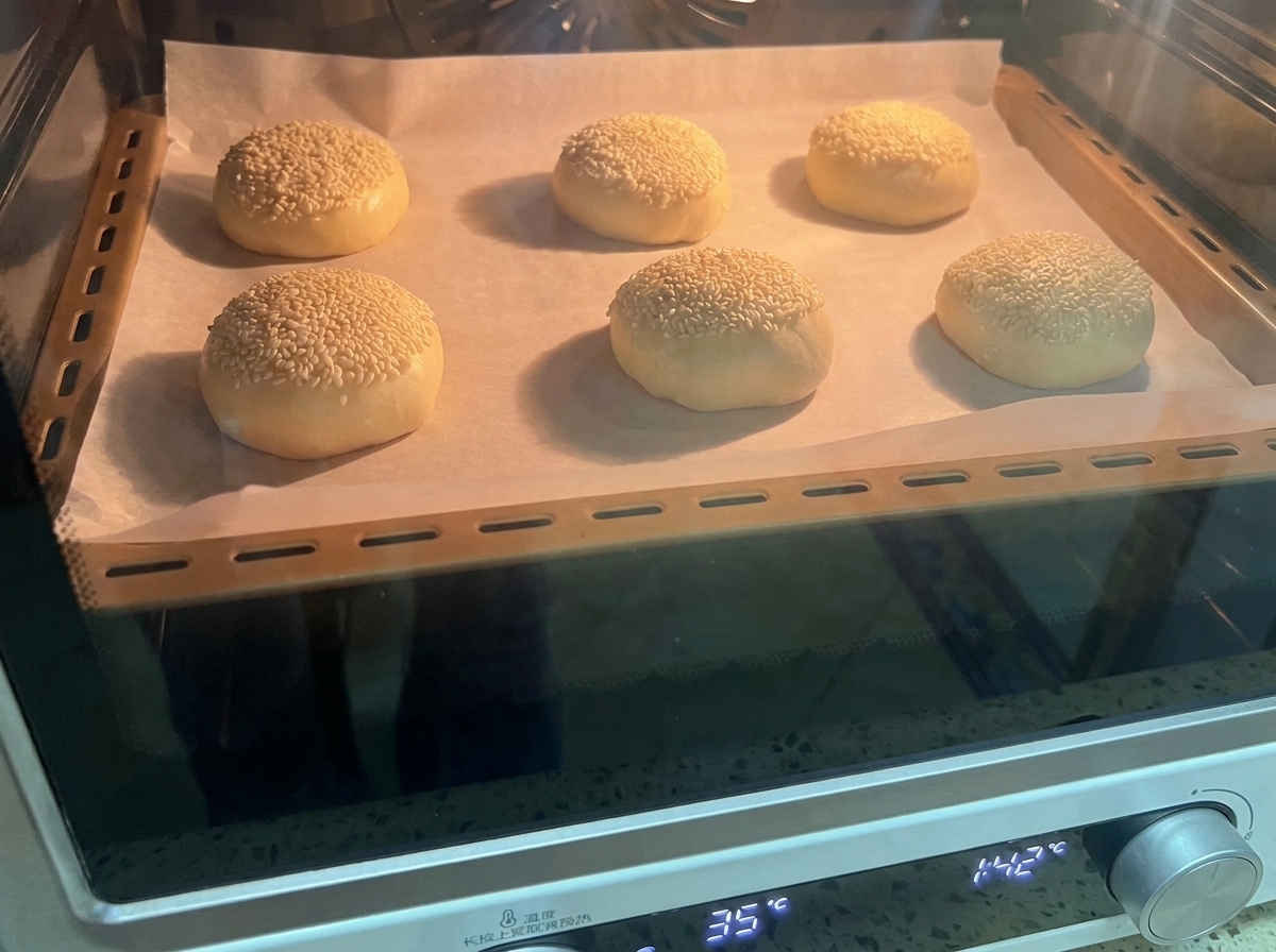 Taca z sześcioma uformowanymi kulkami ciasta w piekarniku.