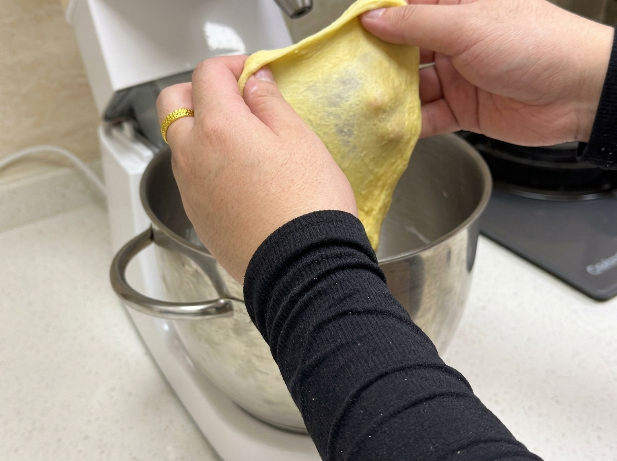 Mała porcja żółtego ciasta jest rozciągana, aby ukazać cienką i elastyczną błonę glutenową.