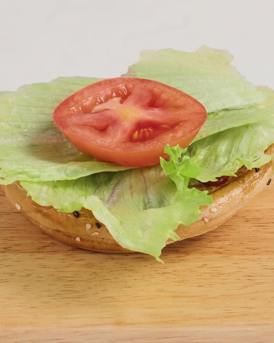 Świeżo złożony burger z sałatą, kotletem wołowym z serem i odrobiną sosu BBQ, gotowy do podania.