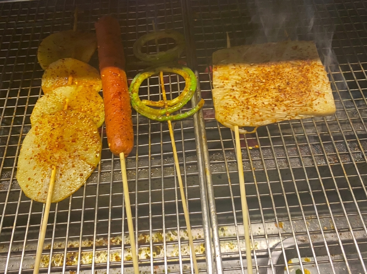Grillowane plastry ziemniaków, kiełbasa i warzywa pokryte sosem BBQ i płatkami chili.